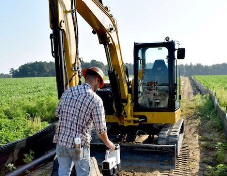 Wes taking measurements in front of excavator
